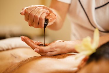Close-up of therapist preparing for hot chocolate massage at the spa. Close-up of massage therapist pouring hot chocolate in her hands before spa treatment.